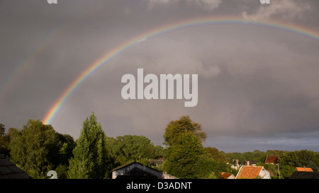 Double rainbow over trees and rooftops Stock Photo