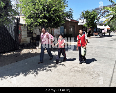 Mexican mother with small daughter & tween son dressed in school uniforms walking home from school on sunny day Oaxaca Mexico Stock Photo