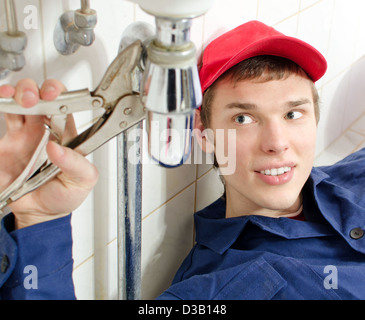 Plumber in uniform repairing old pipeline in the house. Stock Photo