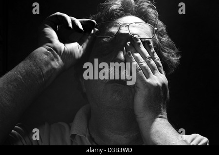 tired middle-aged man rubs his eyes, black and white Stock Photo