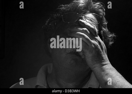 tired middle-aged man rubs his eyes, black and white Stock Photo