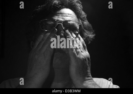 tired middle-aged man rubs his eyes, black and white Stock Photo