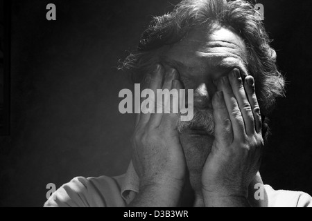 tired middle-aged man rubs his eyes, black and white Stock Photo