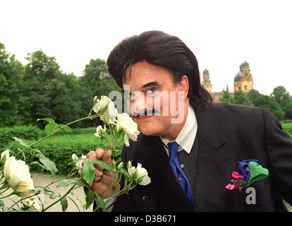 (dpa files) - Rudolph Moshammer, eccentric German fashion designer, smells white roses during a walk in the Hofgarten in Munich, 16 June 1999. After an apprenticeship in a textile company, Moshammer started his career at Christian Dior in Paris. In 1967 he opened, together with his mother, his first Stock Photo