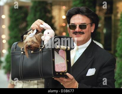 (dpa files) - Rudolph Moshammer, eccentric German fashion designer, presents a new exclusive handbag for dogs, in which he carries his terrier lady called 'Daisy', in front of his shop in the Maximilianstrasse in Munich, 26 February 2000. The leather 'doggy bag' of the 'Moshammer Design Collection'  Stock Photo