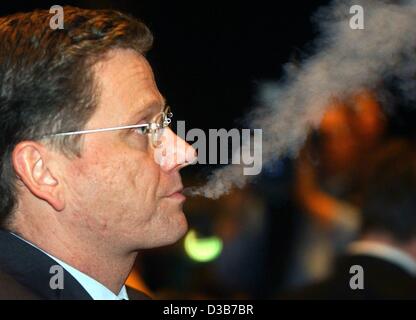 (dpa) - Guido Westerwelle, chairman of the liberal democrats (FDP), is blowing out smoke looking worried, Duesseldorf, 1 December 2002. In his speech at the extraordinary party convention Westerwelle explained why a procedure to expel Juergen Moellemann from the FDP has to be undertaken.