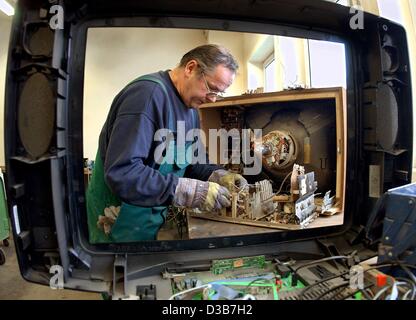 (dpa) - Behind an empty housing of a computer monitor framing the scene, Eckard Ruegen desintegrates an old TV set in Schwerin, Germany, 18 December 2002. According to European guidelines, starting today, computers, toasters or washing machines and other white goods which have come out of use have n Stock Photo