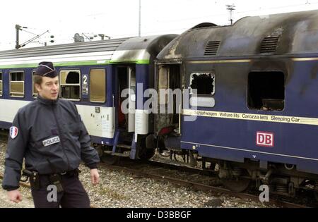 (dpa) - A French policeman walks by the burnt out sleeping car of a train of the Deutsche Bundesbahn (DB) which caught fire shortly before the station of Nancy, 6 November 2002. Twelpe people died, four of them are German. According to the French national railway company SNCF, a technical failure ca Stock Photo