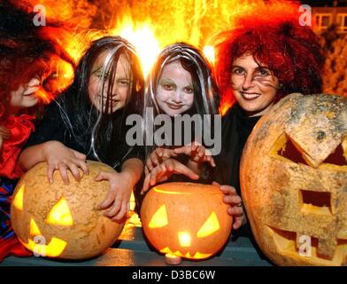 (dpa) - Three 'witches' are showing their glowing Halloween pumpkins, Plessa, Germany, 26 October 2002. The American tradition of carving horrible faces into pumpkins and celebrating Halloween parties is getting more and more popular in Germany. The origin of the tradition, though, goes back two tho Stock Photo