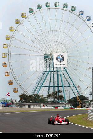 (dpa) - German formula one champion Michael Schumacher races past a ferris wheel of a neighbouring fun fair, during a training in Suzuka, Japan, 11 October 2002. Stock Photo