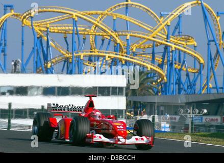 (dpa) - German formula one champion Michael Schumacher races past a rollercoaster at a neighbouring fun fair, during the qualifying training in Suzuka, Japan, 12 October 2002. Stock Photo