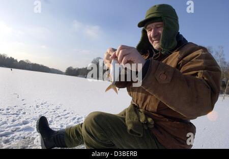 (dpa) - A man dressed in warm winterclothes is happy about a small fish he caught in the frozen Wannsee lake in Berlin, 7 January 2003. Stock Photo