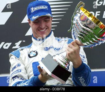(dpa) - German formula one pilot Ralf Schumacher (BMW-Williams) happily holds his trophy after winning the European Grand Prix at the Nuerburgring race track, Germany, 29 June 2003. With 43 points in overall standings for the world championships, he is now ranking third.