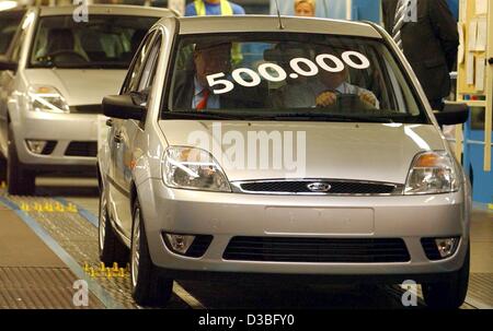 (dpa) - German Chancellor Gerhard Schroeder (covered, R) and Peer Steinbrueck, the Prime Minister of the state of North Rhine Westphalia, drive the 500,000th manufactured Ford 'Fiesta' off the production line at the Ford factory in Cologne, Germany, 23 June 2003. The Ford factory celebrates its 100t Stock Photo
