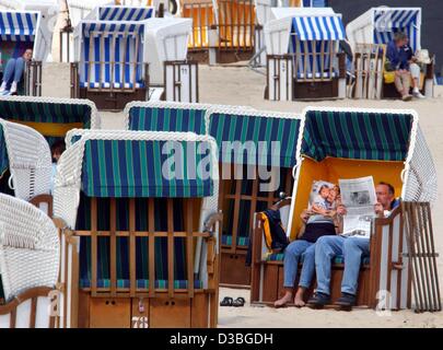 (dpa) - A few holiday makers retire to roofed whicker beach chairs to protect themselves from the cold and the wind, at the Baltic Sea beach on the island Usedom, Germany, 16 May 2003. The traditional German 'Strandkorb' gives protection against sun, wind or rain and can be found at the German coast Stock Photo
