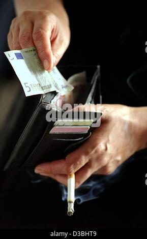 (dpa) - A smoker takes out a 5 euro note from his purse in Berlin, 8 May 2003. The German government has plans to raise the tax on tobacco by one euro to help finance the country's creaking public health insurance funds. The tax increase would bring the price of a package of 19 cigarettes from 3.20  Stock Photo