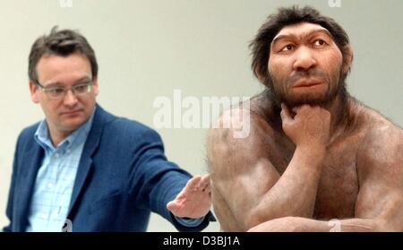 (dpa) - Harald Meller, the director of the museum, gently touches the prehistoric man sitting in the 'Thinker'-pose in the prehistory museum in Halle/Saale, eastern Germany, 17 April 2003. The Neanderthal figure made by the Studio Daynes in Paris is modeled on 250,000 years old skeleton remains. Stock Photo