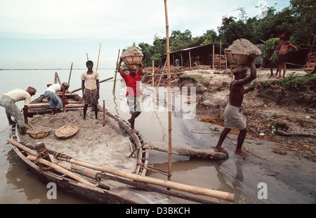 Porters transporting baskets of sand on their heads taken from a local boat for construction and cement making. Shiapur, Bangladesh Stock Photo