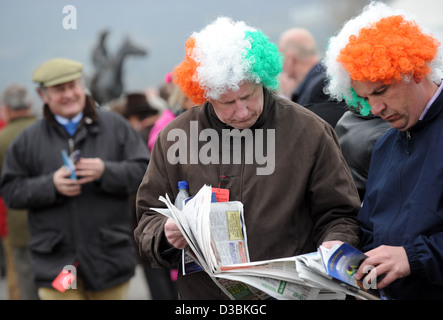 Men wearing tri colour wigs on St Patrick's Day during the Cheltenham Festival, an annual horse racing fixture in England Stock Photo