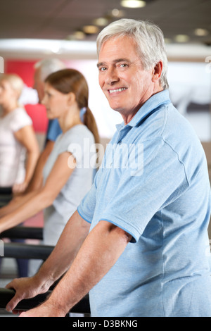 Elderly man exercising on fitness treadmill in gym Stock Photo