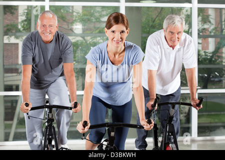 Senior fitness class in gym doing spinning bike exercises Stock Photo