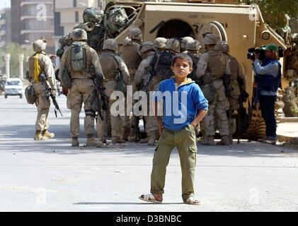 (dpa) - An Iraqi boys stands in front of a group of US soldiers in Iraq, 11 April 2003. The entire medical care in Baghdad has broken down, Red Cross officials said. Hospitals and clinics in the Iraqi capital are closed, the patients have either fled or are left on their own. The rising temperature  Stock Photo