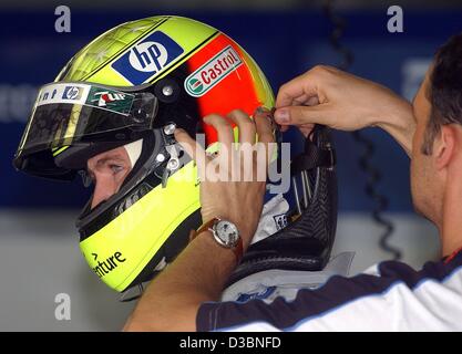 (dpa) - German formula one driver Ralf Schumacher (BMW-Williams) receives support in putting on the HANS system, a head and neck support which protects against the high exposure during the race, on the formula one race track in Kuala Lumpur, Malaysia, 21 March 2003. The formula one grand prix race i Stock Photo