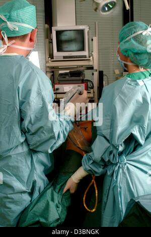 (dpa) - A surgeon and his assistant look at the monitor during an operation on the knee of a patient at the hopsital in Iserlohn, Germany, 11 March 2003. The endoscopic procedure enables the surgeon to undertake an operation with a minimum of effort, while looking at a monitor which displays the are Stock Photo