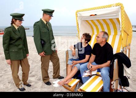 (dpa) - Police officers Ulrike Harenburg and her colleague Mirko Ploetz talk to holiday makers sitting in a typical roofed whicker beach chair on the beach in Zingst, Germany, 12 May 2003. The police patrol along the beach is a new project to make the beaches along the Baltic Sea securer. Stock Photo