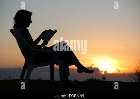 Woman reading at sunset, Las Lajas, Panama Stock Photo
