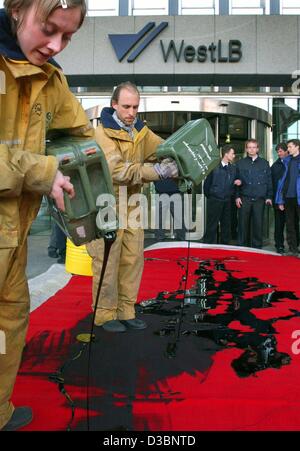 (dpa) - Greenpeace activists spill petrol onto a red carpet in front of the headquarters of the Westdeutsche Landesbank (WestLB) in Duesseldorf, Germany, 16 May 2003. Greenpeace protested against the West LB's financing of an oil pipeline in Ecuador. West LB is Germany's fifth largest bank. Stock Photo
