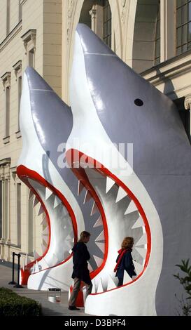 (dpa) - Two visitors enter through the open mouth of sharks the 'Nationalgalerie im Hamburger Bahnhof' (national gallery in the Hamburg train station) in Berlin, 1 October 2003. The sharks, made of steel, styrofoam and fibreglass, are a sculpture by the Australian artist Callum Morton. An exhibition Stock Photo