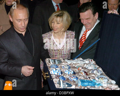 (dpa) - Russian President Vladimir Putin (L) shows German Chancellor Gerhard Schroeder and his wife Doris Schroeder-Koepf a box filled with hand-painted porcelain balls with motifs from Moscow and St. Petersburg, 21 December 2004. Putin handed the gift to the Schroeders ahead of the Christmas celebr Stock Photo