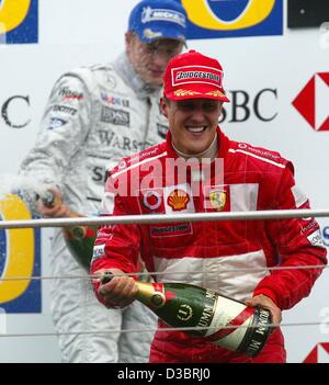 (dpa) - German Formula One world champion Michael Schumacher celebrates on the podium after driving his Ferrari to victory in the US Grand Prix in Indianapolis, 28 September 2003. Schumacher won ahead of Finland's Kimi Raikkonen (background) of McLaren-Mercedes and fellow German Heinz-Harald Frentze Stock Photo