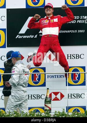 (dpa) - German Formula One world champion Michael Schumacher jumps into the air and celebrates on the podium after driving his Ferrari to victory in the US Grand Prix, while Kimi Raikkonen walks away in the background in Indianapolis, 28 September 2003. Schumacher won ahead of Finland's Kimi Raikkon Stock Photo