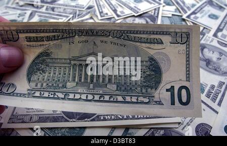 (dpa) - A hand holds up ten dollar banknote in front of a pile of dollar bills in Berlin, 25 August 2003. Stock Photo