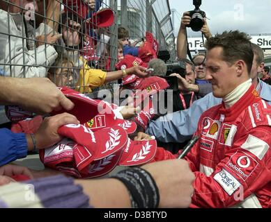 (dpa) - German formula one pilot and world champion Michael Schumacher (Ferrari) signs autographs for his fans at the Nuerburgring formula one racetrack. The five time winner of the world champion title takes some time out for his fans before the start of the all deciding phase in the race for the w