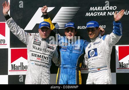 (dpa) - Spain's Fernando Alonso of Renault (C) is flanked by second placed Finnish Kimi Raeikkoenen (L) of McLaren-Mercedes and third placed Colombian Juan Pablo Montoya of BMW-Williams after the Hungarian Grand Prix in Budapest, 24 August 2003. Alonso made Formula One history by becoming the younge Stock Photo