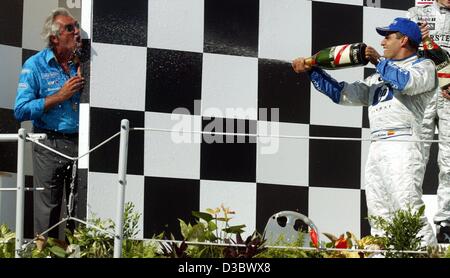 (dpa) - Third-placed formula one pilot Juan Pablo Montoya of BMW-Williams sprays champagne at Renault's team chief Flavio Briatore (L) after the Hungarian Grand Prix in Budapest, 24 August 2003. Renault's Fernando Alonso won the race. Stock Photo