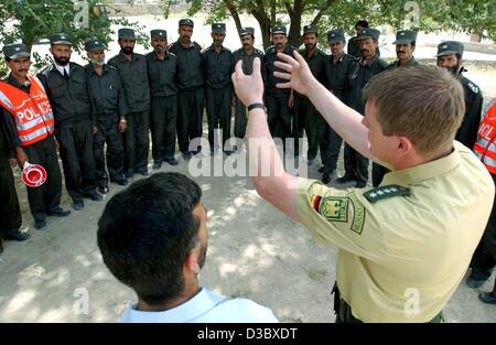 (dpa) - An officer (R) of the German Federal Border Guard explains to a group of Afghan police recruits how to behave during a police inspection of vehicles and cars on the premises of the police academy in Kabul, Afghanistan, 4 August 2003. The responsibility of public safety lies with the Internat Stock Photo