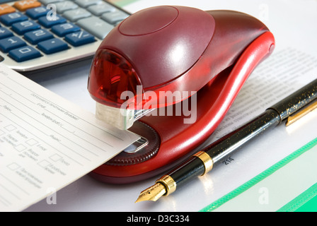 Stapler of red color, pen and calculator Stock Photo