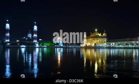The Golden Temple and minarets glowing in the night with its reflection in the sacred pool. Stock Photo