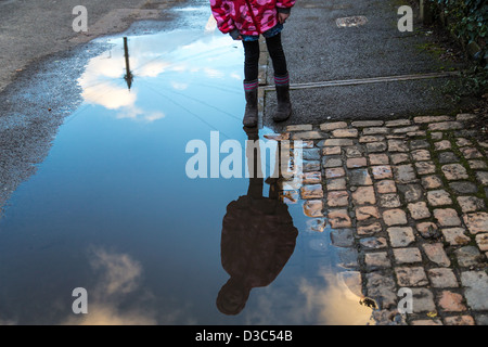 Girl stares at her reflection in a Puddle Stock Photo