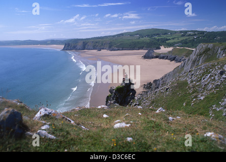 Lone male walker sitting on rock overlooking Three Cliffs Bay Gower Peninsula South Wales UK Stock Photo