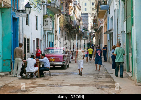 Busy street scene and red old 1950s vintage American car / Yank tank in Old Havana / La Habana Vieja, Cuba, Caribbean Stock Photo