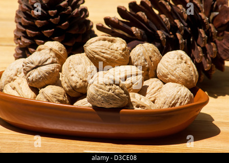 Close-up of walnuts in a ceramic bowl an pine cones Stock Photo