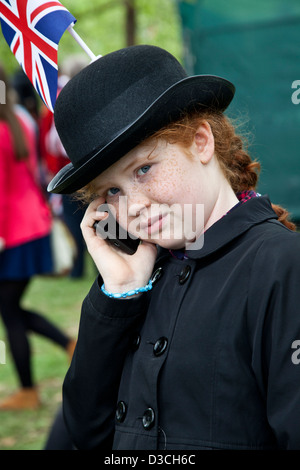 British girl wearing a  a bowler hat with the Union Jack is talking on mobile phone during Queen Elisabeth II Diamond Jubilee Stock Photo