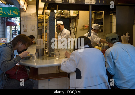 Patrons enjoy good, cheap food at counter eatery restaurant in the backstreet Omoide Yokocho, or Memory Lane, in Shinjuku, Tokyo Stock Photo