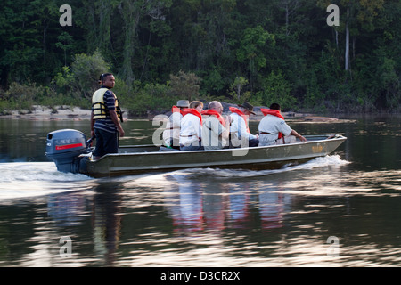 Eco-tourists and guide on a motor launch for an evening on the Essequibo River. Stock Photo