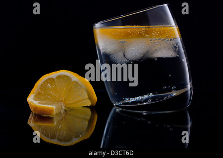 Gin and tonic or vodka and tonic with a slice of lemon over black Stock Photo